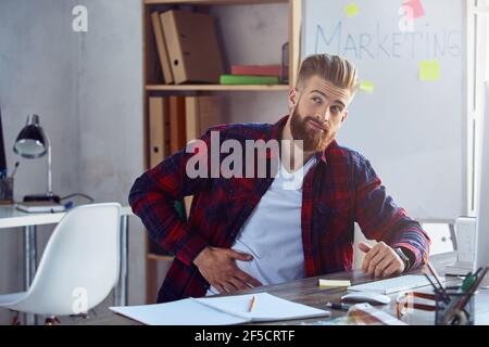 Un jeune homme malsain est assis au bureau Banque D'Images