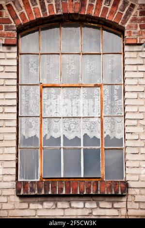 ancienne fenêtre de maison en briques rouges avec rideaux blancs Banque D'Images
