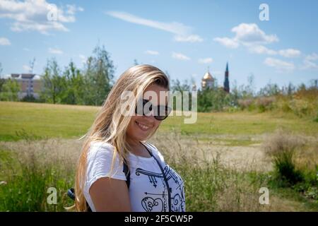 Une belle jeune fille en lunettes de soleil se promène dans la ville. Les cheveux longs blonds flitter dans le vent. Moscou Russie 20 juin 2018 Banque D'Images