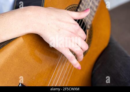 De dessus anonyme femme avec manucure jouant de la guitare acoustique pendant session musicale en studio Banque D'Images