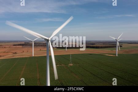 Vue aérienne d'un parc éolien sur des terres agricoles vertes avec de grandes éoliennes blanches générant de l'électricité renouvelable verte pendant une crise énergétique Banque D'Images