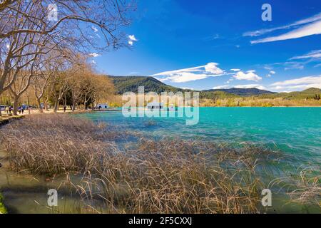 Vue panoramique sur la rive du lac Banyoles où un chemin le borde avec d'énormes arbres, où les touristes marchent. Banyoles, Catalogne, Espagne Banque D'Images