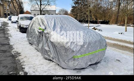 Voiture sous bâche sur route enneigée en hiver, Allemagne Banque D'Images