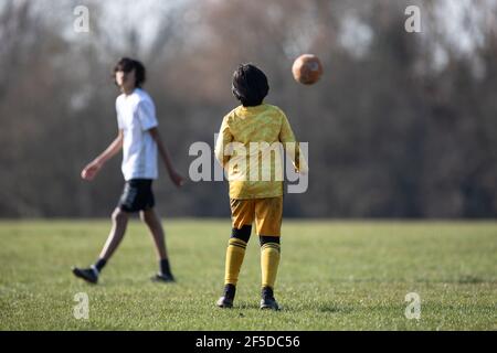 Oadby, Leicestershire. Angleterre. Mars 2021. Les garçons jouent au football dans un parc local. Banque D'Images