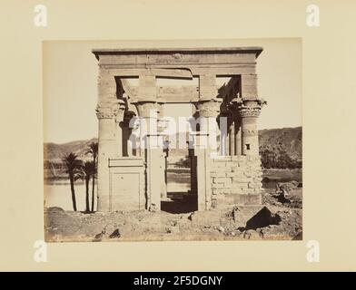 Phyloe. Temple Hypêthre, vue de facè, Égypte. Vue sur une structure en pierre avec colonnes de papyrus et sans toit. Ses deux passerelles sont parallèles les unes aux autres et mènent à un plan d'eau en arrière-plan. Un homme natif est assis près de la porte d'entrée. (Recto, print) en bas à gauche, inscrit dans le négatif: 'Phyloe. Temple HypÍthre, vue de facË barre oblique …gitte barre oblique. 185.'; Banque D'Images