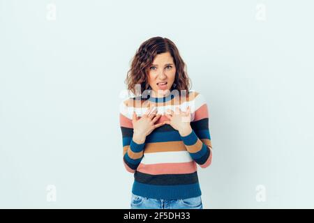 Mécontent, la jeune femme en colère se montre avec ses mains tout en se tenant sur un fond blanc. Banque D'Images