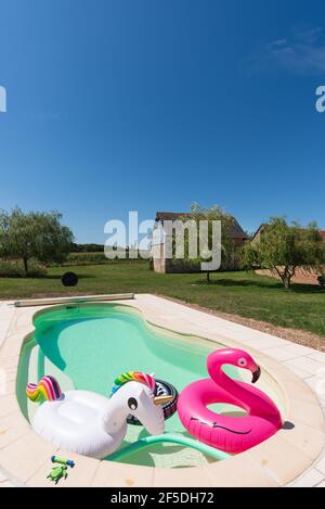 Jouets de piscine dans une piscine extérieure sous un ciel bleu vif. Banque D'Images