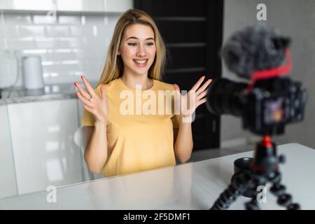 Femme attrayante enregistrant un blog vidéo sur un appareil photo reflex numérique dans la cuisine à la maison Banque D'Images