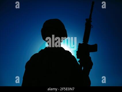 Silhouette nocturne des forces des opérations spéciales de l'armée soldat debout avec une carabine de service sur fond de ciel nocturne avec lune et étoiles. Combattant de guerre moderne en casque, Raider de Marines dans l'obscurité Banque D'Images