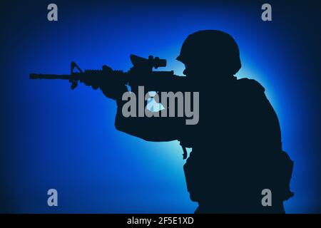 Soldat d'infanterie de l'armée moderne, rifleman de la garde côtière visant le fusil d'assaut avec collimateur de vue la nuit. Des opérations spéciales forces de combat engageant l'ennemi dans l'obscurité, observant le territoire pendant la mission Banque D'Images