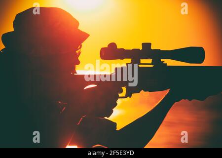 Sniper de l'équipe de commando, tir de tir des forces spéciales de l'armée, tir de fusil de sniper tout en étant assis sur la mer ou sur la côte de l'océan pendant le coucher du soleil. Un soldat de la côte ou du garde-frontière observe la côte avec une vue optique Banque D'Images