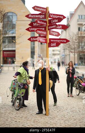 26 Mars 2021, Saxe-Anhalt, Halberstadt: L'artiste Thomas Peters de Quedlinburg se dresse sur la place du marché à Halberstadt et porte un arbre de signalisation à pied de Halberstadt à Quedlinburg. Avec cette action, l'artiste veut attirer l'attention sur la situation de la scène artistique et culturelle. Les signes avec environ 20 termes différents symbolisent également le fardeau de la vie, explique Thomas Peters, qui veut donner l'exemple. Photo: Matthias Bein/dpa-Zentralbild/dpa Banque D'Images