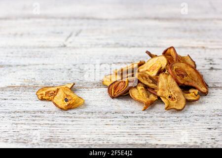 Pile de poires séchées en tranches sur fond de bois blanc. Croustilles de fruits séchées. Une alimentation saine Banque D'Images