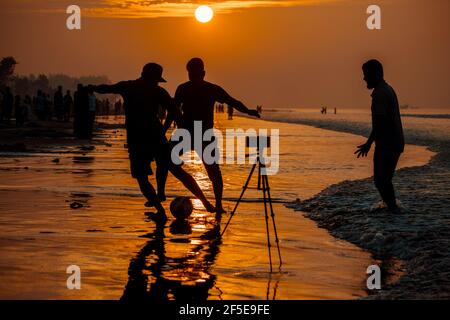 Trois amis jouant au football sur la plage. Banque D'Images