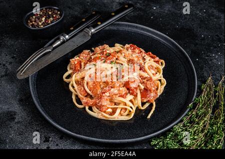 Pâtes Feta tendance avec tomates cerises cuites au four et fromage sur une assiette. Arrière-plan noir. Vue de dessus Banque D'Images