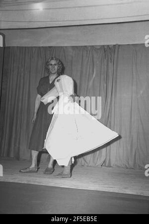 1954, historique, sur une scène devant le rideau portant des costumes, un grand acteur masculin dans la robe et la perruque d'une femme et la «autre oie», se présentant dans le pantomime, «autre OIE», Angleterre, Royaume-Uni. À l'origine l'auteur imaginaire d'une collection de contes de fées français et plus tard de comptines anglaises, il est dit que le personnage est apparu pour la première fois en 1806 comme la performance, 'Arlequin et mère Goose ou l'oeuf d'or'. Les différentes adaptations pantomime de l'histoire de la mère Goose se sont poursuivies tout au long des XIXe et XXe siècles et il est resté un spectacle de divertissement familial populaire. Banque D'Images