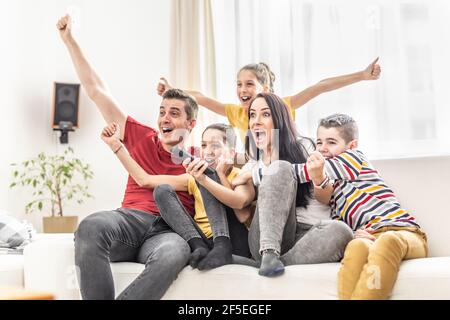 Une famille enthousiaste de cinq acclamations à la maison pour regarder des sports TÉLÉVISION Banque D'Images