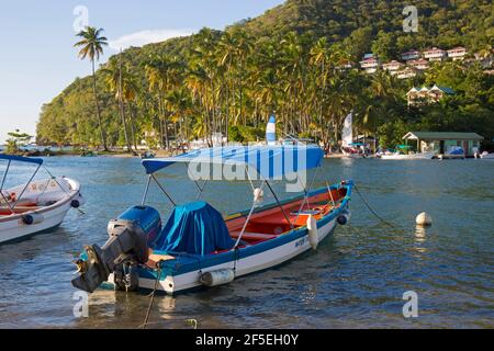 Marigot Bay, Castries, Sainte-Lucie. Bateau-taxi coloré amarré au bord de l'eau, LABAS Beach en arrière-plan. Banque D'Images