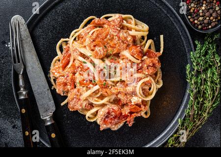 Pâtes Feta tendance avec tomates cerises cuites au four et fromage sur une assiette. Arrière-plan noir. Vue de dessus Banque D'Images