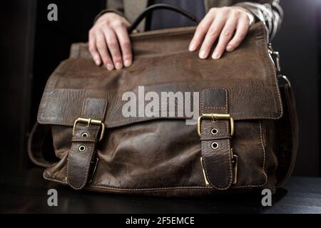 Les mains des femmes enseignantes se tiennent sur une mallette en cuir brun antique. Banque D'Images