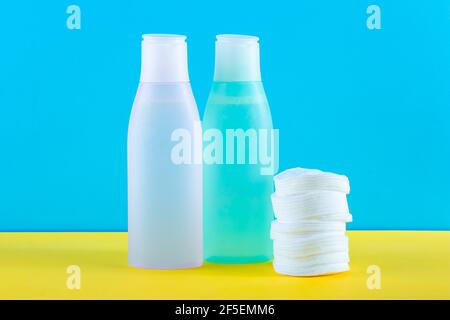 Deux bouteilles cosmétiques avec eau micellaire et tampons de coton. Concept de soin du visage. Fond papier jaune et bleu. Démaquillant. Toner frontal sur ta Banque D'Images