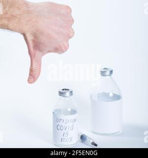 Pouce vers le bas pour le mauvais vaccin dans des bouteilles médicales en verre sur un fond blanc. Banque D'Images