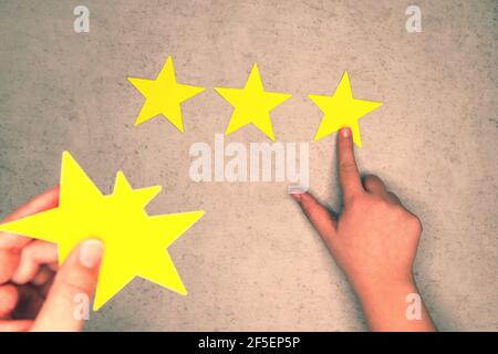 Concept d'expérience client. Trois étoiles jaunes sur fond de béton. Feedback négatif - sélection manuelle d'un 3 étoiles Banque D'Images