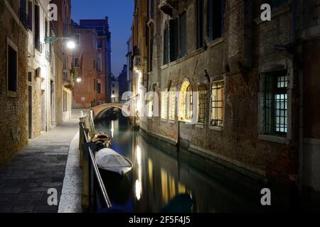 Vue de nuit sur le canal à Venise avec pont lumineux, maisons et bateaux, Italie Banque D'Images