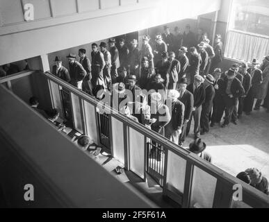 L'aide au chômage commence. Ligne d'hommes à l'intérieur d'un bureau de division du bureau du Service de l'emploi de l'État à San Francisco, en Californie, attendant de s'inscrire pour les prestations l'un des premiers jours où le bureau a été ouvert. Ils recevront de six à quinze dollars par semaine pour un maximum de seize semaines. Coïncidente avec l'annonce que le recensement fédéral du chômage a révélé que près de dix millions de personnes n'avaient plus de travail, vingt-deux États commencent à payer des indemnités de chômage. Janvier 1938. Photo de Dorothea Lange. Banque D'Images