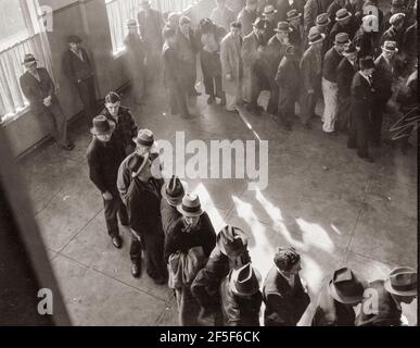 L'aide au chômage commence. Ligne d'hommes à l'intérieur d'un bureau de division du bureau du Service de l'emploi de l'État à San Francisco, en Californie, attendant de s'inscrire pour les prestations l'un des premiers jours où le bureau a été ouvert. Ils recevront de six à quinze dollars par semaine pour un maximum de seize semaines. Coïncidente avec l'annonce que le recensement fédéral du chômage a révélé que près de dix millions de personnes n'avaient plus de travail, vingt-deux États commencent à payer des indemnités de chômage. Janvier 1938. Photo de Dorothea Lange. Banque D'Images