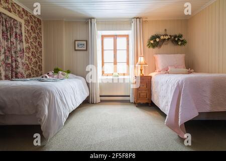 Deux lits simples et table de nuit en pin dans la chambre avec moquette verte à l'étage à l'intérieur d'une ancienne 1807 maison de style cottage Banque D'Images