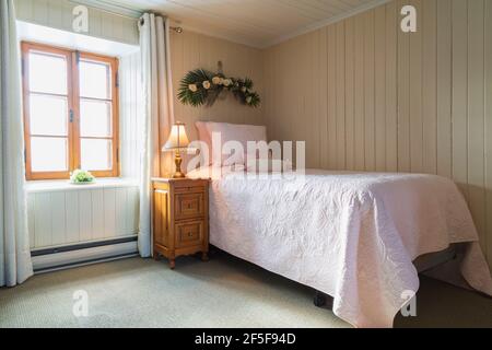 Lit simple et table de nuit en pin dans la chambre avec moquette verte à l'étage à l'intérieur d'un ancien cottage de 1807 maison de style Banque D'Images