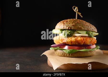 Hamburger végétalien de pains à la spiruline, sauce au pesto, légumes, boulettes de carottes sur fond noir. Gros plan. Banque D'Images