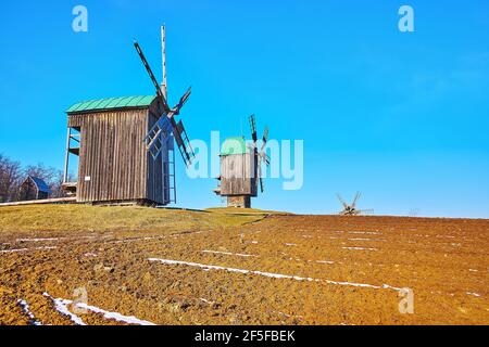 Pyrohiv Skansen possède des moulins à vent en bois conservés, situés au sommet de la colline, à côté du champ labouré, Kiev, Ukraine Banque D'Images