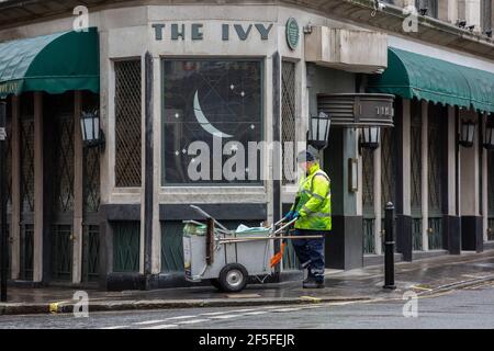 Le balai de route passe par l'extérieur du restaurant Ivy alors qu'il reste fermé en raison des restrictions gouvernementales liées à la pandémie du coronavirus, Londres, Royaume-Uni Banque D'Images