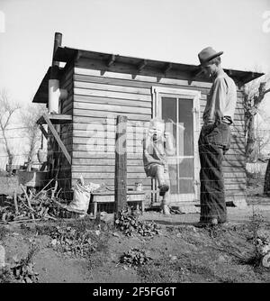 Madera County, famille de près de Dallas, Texas. Le loyer est de cinq dollars par mois. « il n'y a pas d'avenir ici. J'ai suivi le travail (travail migratoire) mais il n'y a aucune chance pour un collègue d'obtenir un hisself holt dans ce pays. Le dernier travail que j'ai eu est de conduire un tracteur pendant trente-cinq cents l'heure. A eu ce travail pendant cinq mois jusqu'à ce qu'un philippin arrive pour vingt-cinq cents l'heure. J'ai été élevé dans une ferme de coton mon père a possédé un petit endroit là-bas et je suis prêt à quitter ce pays pour de bon avant que je ne sois trop vieux, si j'ai pu avoir la chance de cultiver.'Fév 1939.Photographie par Dorothea Lange Banque D'Images