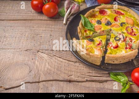 Quiche maison Lorraine, tarte salée au saumon, brocoli, épinards et tomates, sur fond de table en bois Banque D'Images