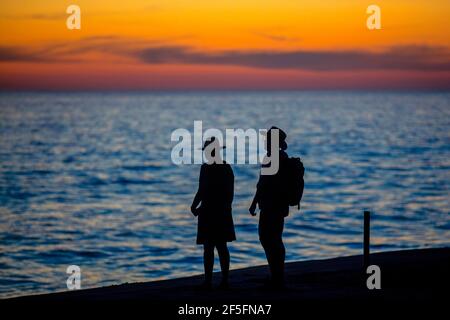 Silhouette de couple mexicain regardant le coucher de soleil sur l'océan Pacifique Nord depuis la plage près de Puerto Escondido, San Pedro Mixtepec, Oaxaca, Mexique Banque D'Images