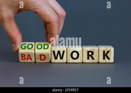 Symbole de bon ou mauvais travail. Homme d'affaires transforme des cubes en bois et change les mots « mauvais travail » en « bon travail ». Magnifique arrière-plan gris, espace de copie. Affaires a Banque D'Images