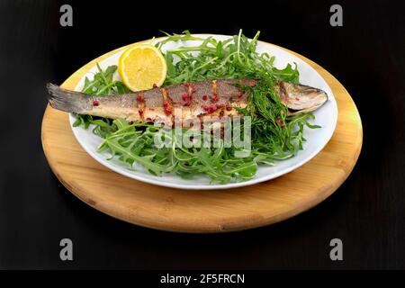 Bar de toute la mer sur un lit de fusée servi avec aneth, citron et grains de poivre rose Banque D'Images