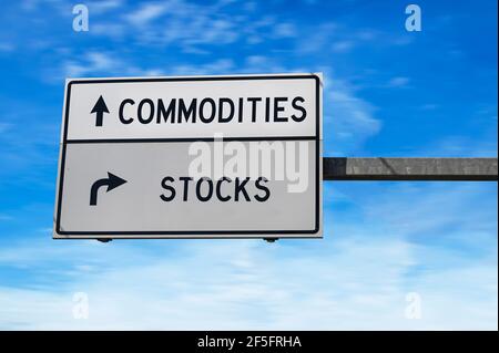 Signalisation routière avec les mots marchandises et stocks. Deux panneaux de signalisation blancs avec flèche sur poteau métallique. Route directionnelle, panneau Crossroads Road, deux flèches sur blu Banque D'Images