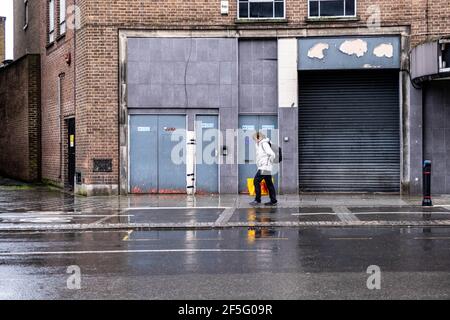 Londres, Royaume-Uni, le 26 2021 mars, une femme passe devant un bâtiment vide lors D'UNE journée humide lors du programme d'éclusage du coronavirus Coovid-19 Banque D'Images