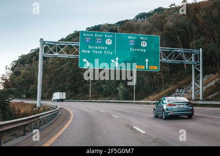 Voitures sur l'autoroute dans le pays de la ville américaine. Route vers la ville de New York. Panneaux verts bleus pour la ville de New York. Autoroute à vide en plein air, en été. Banque D'Images