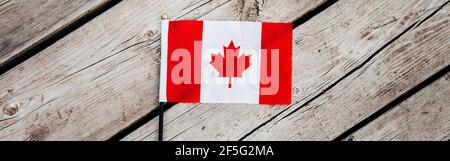 Drapeau canadien rouge avec feuille d'érable rouge sur des planches de bois arrière-plan à l'extérieur. Symbole du drapeau canadien lors de la célébration nationale de la fête du Canada le 1er juillet. Vie Banque D'Images