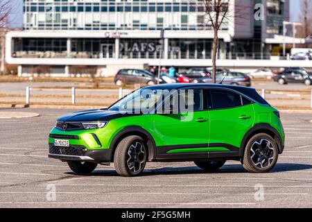 Riga, Lettonie - 26 mars 2021: Véhicule électrique vert Opel Mokka-e dans le parking sur le fond d'une zone résidentielle urbaine Banque D'Images