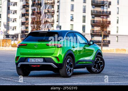 Riga, Lettonie - 26 mars 2021: Véhicule électrique vert Opel Mokka-e dans le parking sur le fond d'une zone résidentielle urbaine Banque D'Images