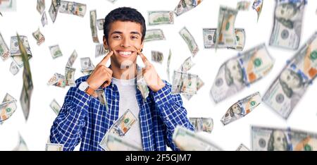 Jeune homme amérindien africain portant des vêtements décontractés souriant à la bouche ouverte, les doigts pointant vers le haut et forçant le sourire joyeux Banque D'Images