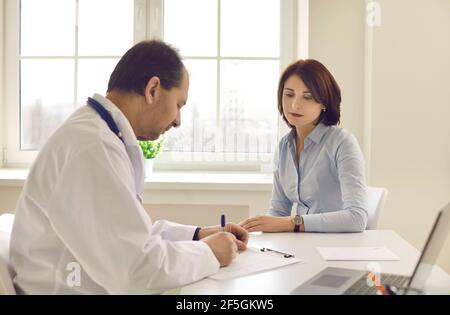 La patiente regarde le médecin qui écrit une ordonnance lors de la réunion bureau médical Banque D'Images