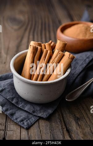 Condiment alimentaire sain avec des propriétés médicinales, de véritables bâtons de cannelle de Ceylon et de la poudre dans un bol sur fond de bois Banque D'Images