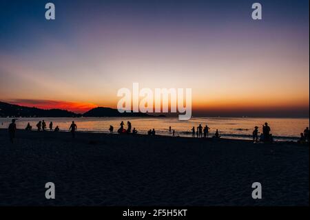 Silhouettes de personnes sur la plage. Lancement de ballons d'air chaud en papier de riz dans le ciel au coucher du soleil sur une plage en Thaïlande Banque D'Images